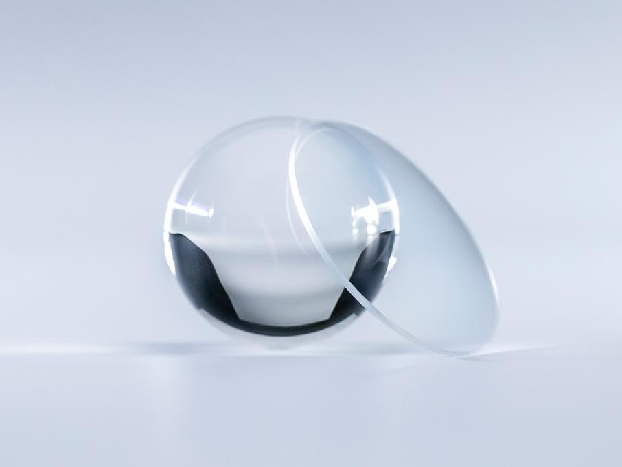 Leća sa ZEISS Platinum slojem kristalno je čista bez refleksija u usporedbi sa staklenom kuglom pored nje.