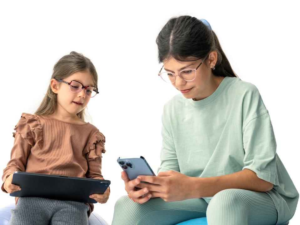 Dvije djevojke gledaju u digitalne uređaje na preporučenoj udaljenosti većoj od 20 cm.