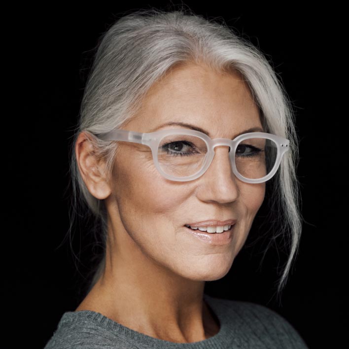 Žena sa sijedom kosom nosi bijeli okvir sa ZEISS SmartLife progresivnim lećama. Geometrijsko skeniranje lica koje prikazuje mjerenja anatomije lica i okvira.